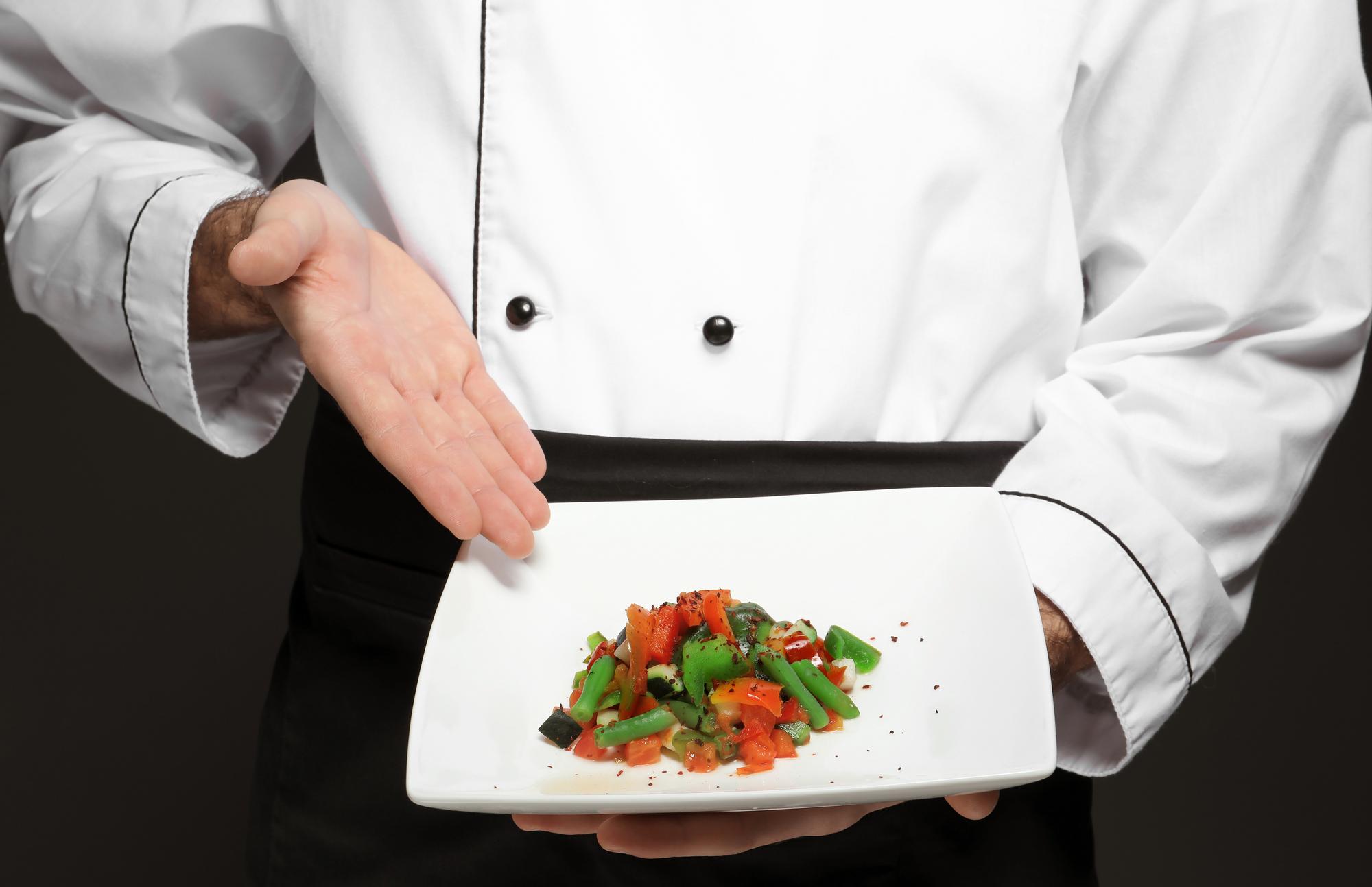 Chef demonstrating plated dish in studio